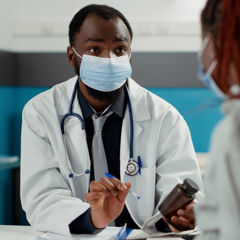 Maternity specialist and pregnant woman with face mask at checkup visit Maternity specialist and pregnant woman with face mask at checkup visit, meeting to talk about pregnancy. Future mother with baby bump asking for medical advice from physician at cabinet desk.